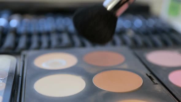 Close up View of Makeup Brush Moving Over Skin and Eyeshadow Color Palette alt