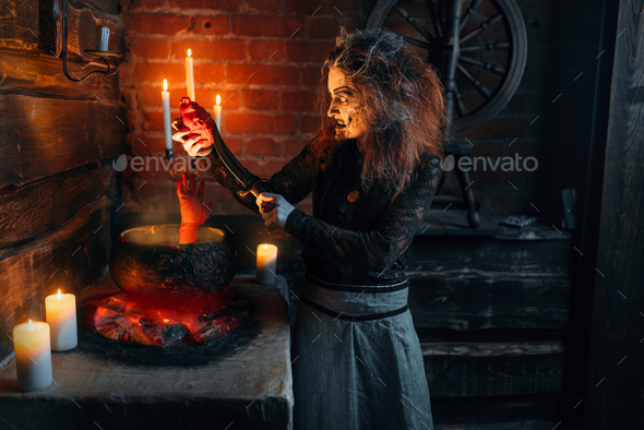 Scary witch cooking soup with human body parts - Stock Photo - Images