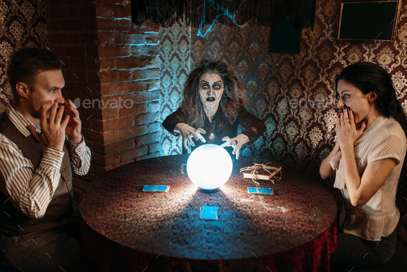 Witch reads scary spell over a crystal ball - Stock Photo - Images