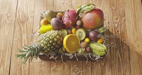 The motion of sunlight above the wooden box with fresh natural organic tropical fruits on a wooden