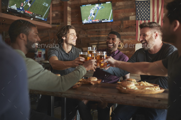 Male Friends Drinking Beer And Eating Burgers In Sports Bar