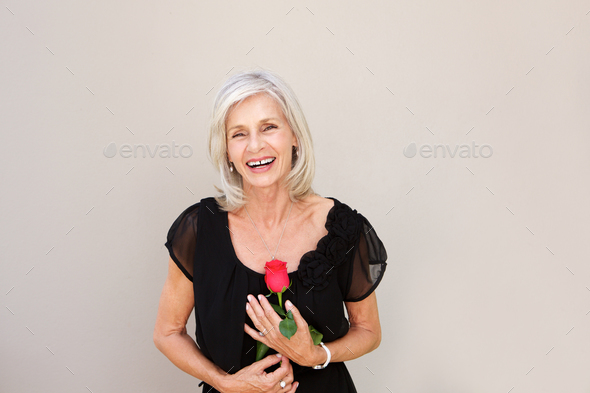 beautiful older woman laughing with red rose in black blouse