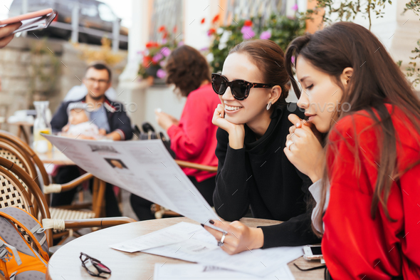 Two beautiful stylish women sitting at the table in street cafe - Stock Photo - Images