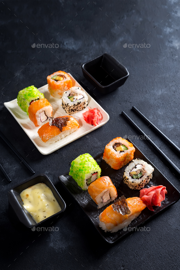 Traditional Japanese food- sushi, rolls, chopsticks, soy sauce on black slate background. Sushi menu