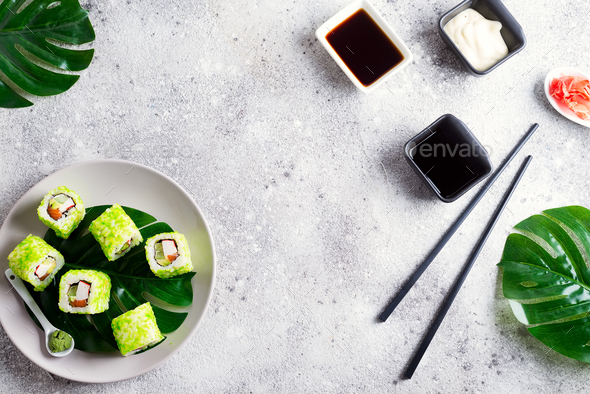 sushi roll with green caviar on a plate with chopsticks on stone background . Flat lay Sushi menu