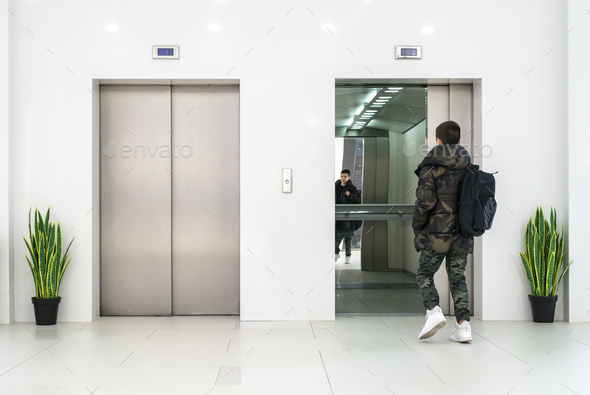 Teenager boy with casual clothes and white sneakers enters in el - Stock Photo - Images