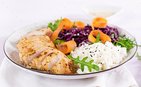 Buddha bowl dish with chicken fillet, rice, red cabbage, carrot, fresh lettuce salad and sesame.