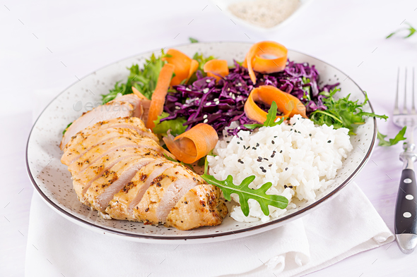 Buddha bowl dish with chicken fillet, rice, red cabbage, carrot, fresh lettuce salad and sesame