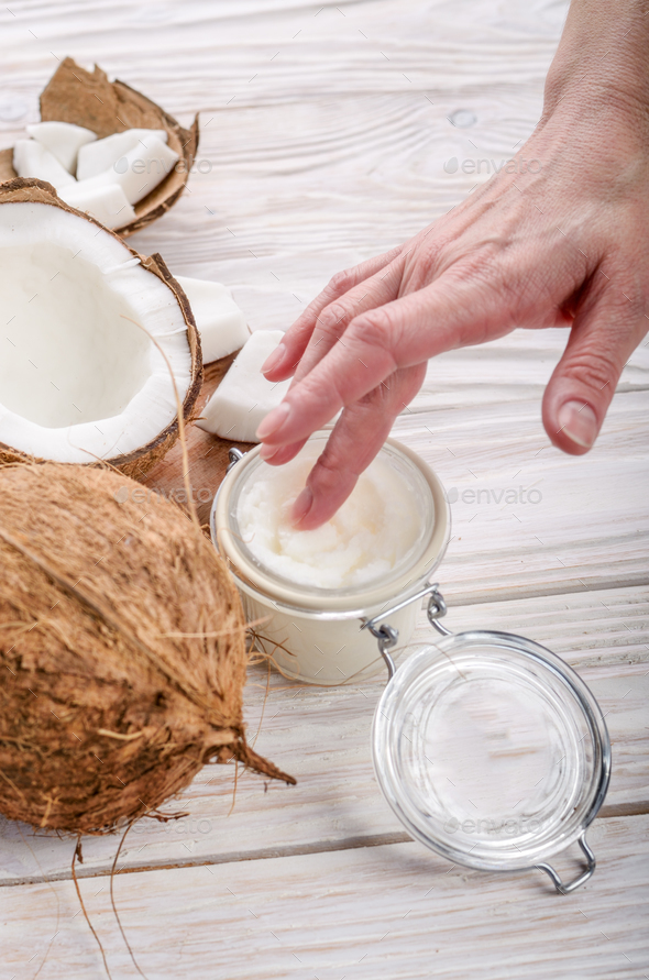 Coconut oil on human palm and in airtight glass jar with shell p - Stock Photo - Images