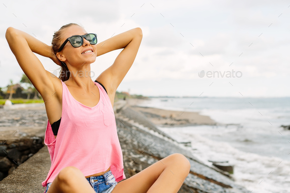 Beautiful girl in sporty outfit on the ocean beach.
