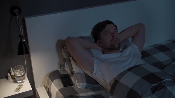 Lonely Man Cannot Sleep in Bed at Night with Eyes Wide Open Staring at Ceiling alt