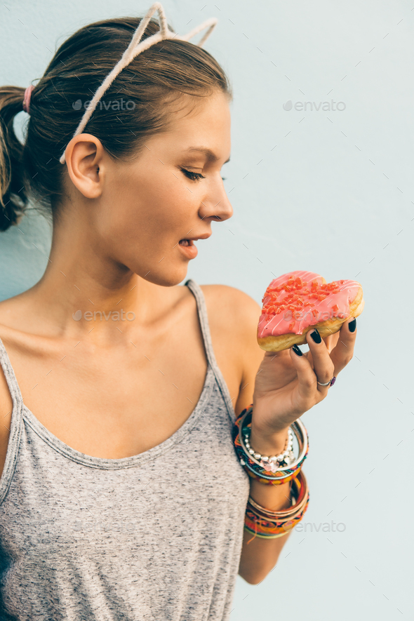 Sexy brunette lady eat sweet heart shaped donut. - Stock Photo - Images
