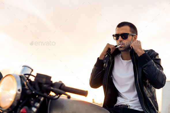 Brutal man sit on cafe racer custom motorbike.