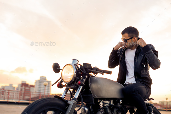 Brutal man sit on cafe racer custom motorbike.