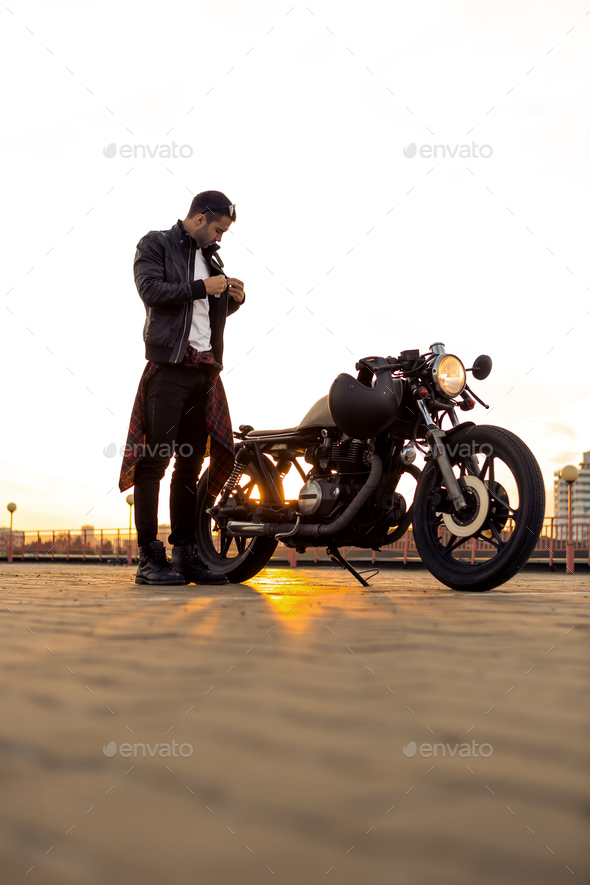 Brutal man near his cafe racer custom motorbike. - Stock Photo - Images