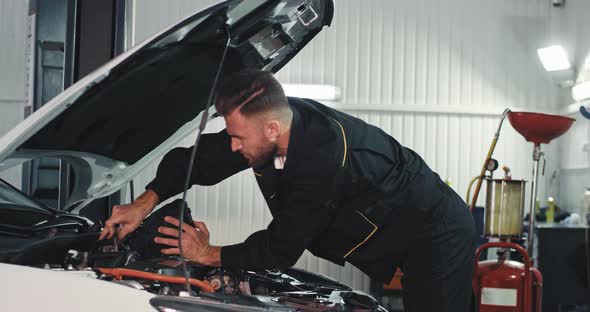 Good Looking Mechanic Guy Working on a Service alt