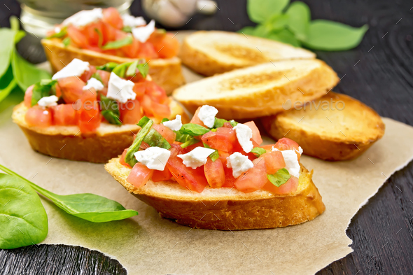 Bruschetta with tomato and cheese on dark board - Stock Photo - Images
