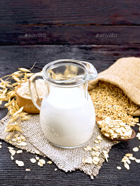 Milk oatmeal in jug on dark wooden board - Stock Photo - Images