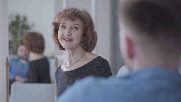 Cute Elegant Mature Woman Talking with Her Partner Sitting at Home on the Sofa Close Up. Reflection alt