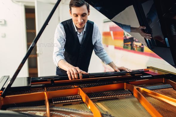 Pianist sets the grand piano before performance - Stock Photo - Images