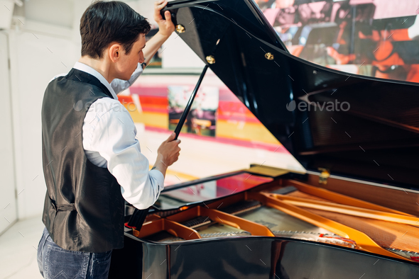 Male pianist opens the lid of black grand piano - Stock Photo - Images