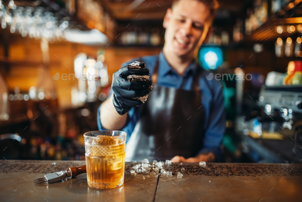 Male bartender works with ice at the bar counter - Stock Photo - Images