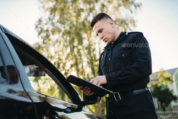 Policeman in uniform writes fine to female driver - Stock Photo - Images