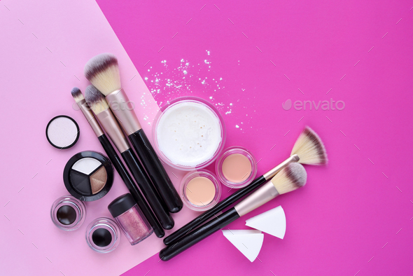 Makeup brush and decorative cosmetics on pink background. Top vi