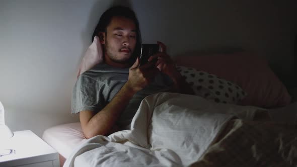 Young Asian men using a smartphone browsing web and scroll through social media feed.