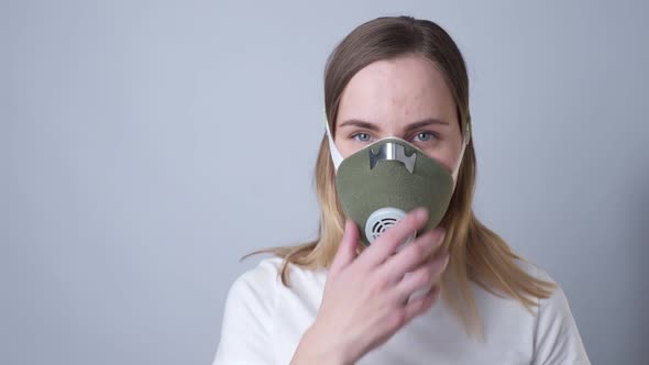 Close-up Portrait of a Woman Removes a Respiratory Face Mask During the Quarantine of the COVID-19 alt