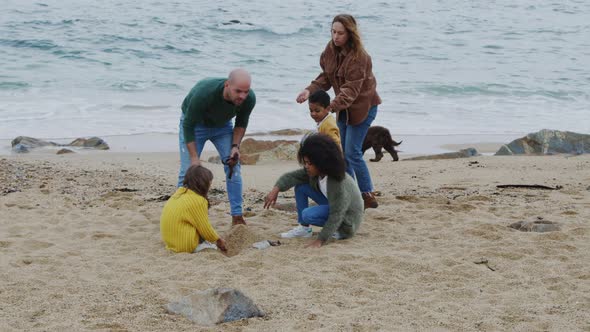 Parents and Children Construct Sand Castle On Beach