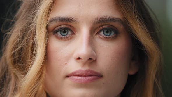 Extreme Closeup Female Young Face with Perfect Skin Blue Eyes Looking at Camera Often Blinks Feels alt