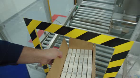 A Pharmaceutical Production Worker Takes the Box with a Packaged Batch of Medicine From the Assembly