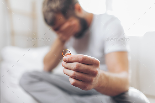 Heartbroken man holding a wedding ring