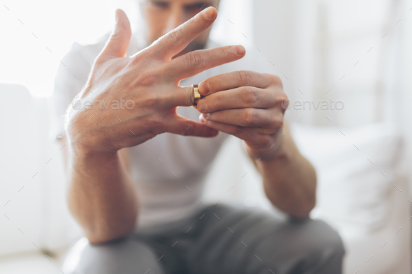Heartbroken man holding a wedding ring