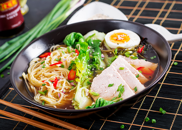 Miso Ramen Asian noodles with egg, pork and pak choi cabbage in bowl on dark background.