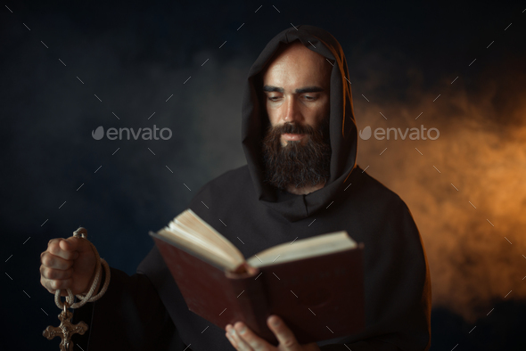 Medieval monk praying with book in church - Stock Photo - Images