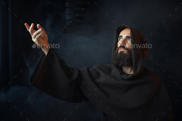 Medieval monk praying against a window with light - Stock Photo - Images