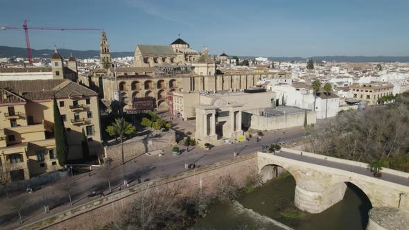 Roman bridge of Cordoba leads toward city gate, Mezquita in background; drone