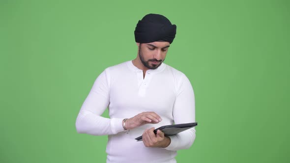Young Happy Bearded Indian Man Using Digital Tablet