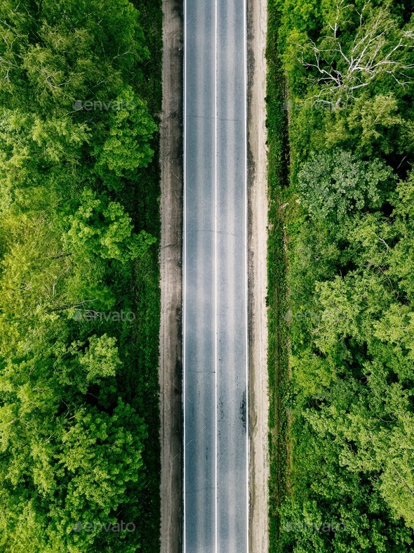 Aerial view of empty road going through green forest. - Stock Photo - Images