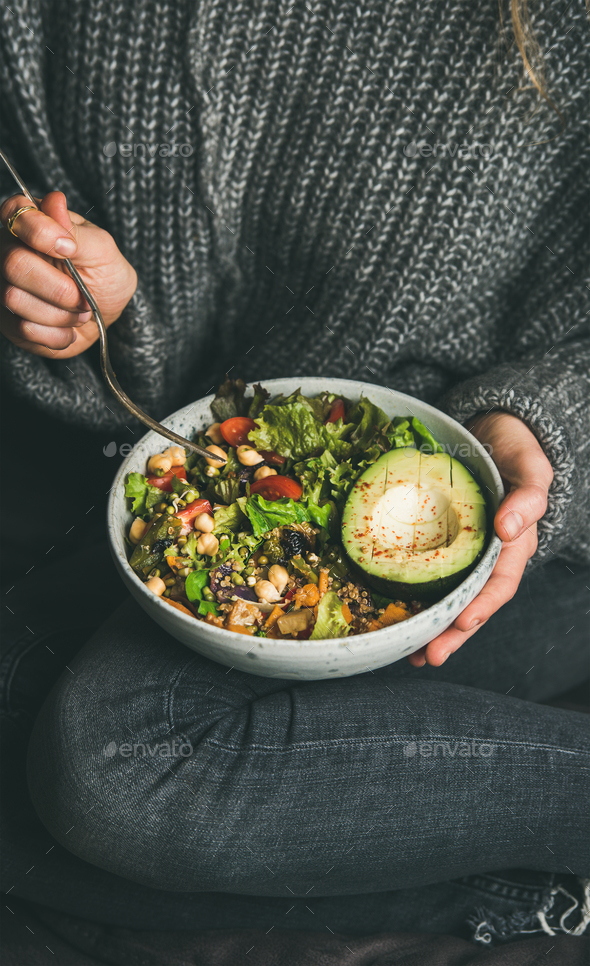 Woman sitting and eating healthy vegetarian dinner from Buddha bowl - Stock Photo - Images