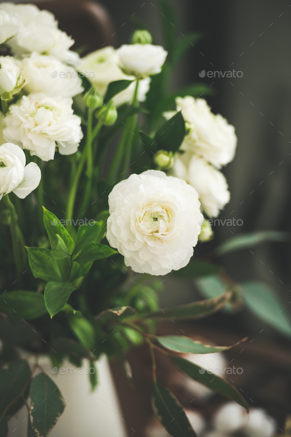 Spring white buttercup flowers in enamel jug, curtain behind - Stock Photo - Images