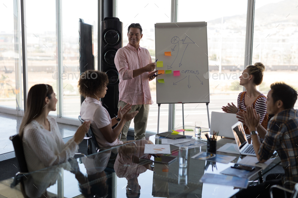 Business executive using a flip chart board for explain his plan to his colleagues in a office - Stock Photo - Images
