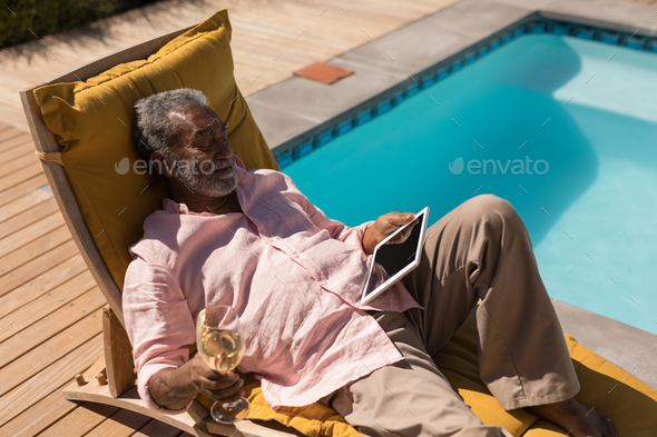 Senior Man Having Champagne On The Lounger Chair Next To The Swimming Pool