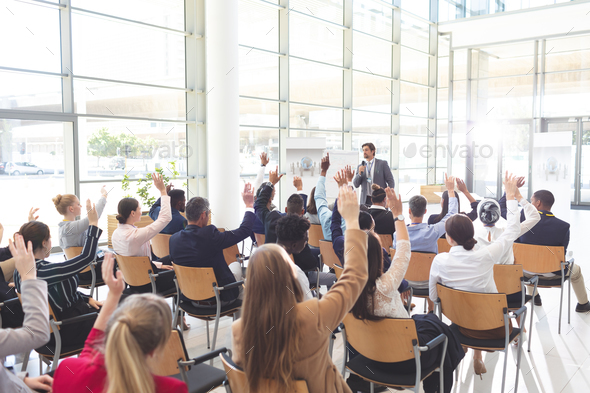 Diverse business people listening and raising hands in conference - Stock Photo - Images