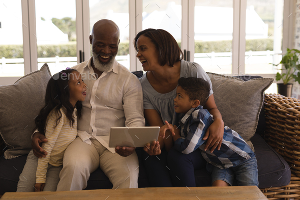 Happy multi-generation African American family using digital tablet in living room at home
