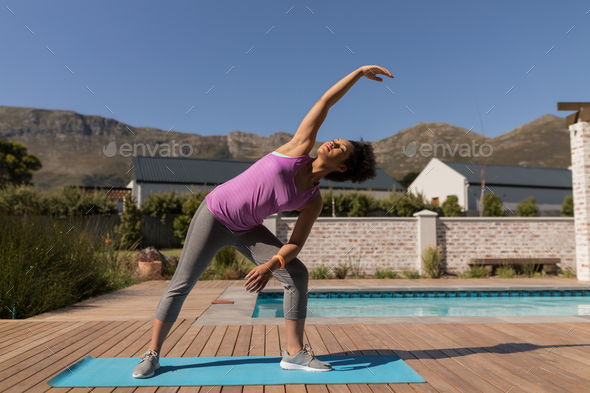 Young African American woman performing stretching exercise next to the swimming pool - Stock Photo - Images
