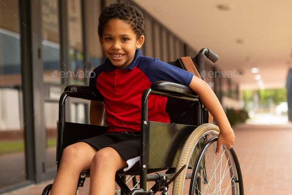 Smiling disabled schoolboy looking at camera in corridor at elementary ...