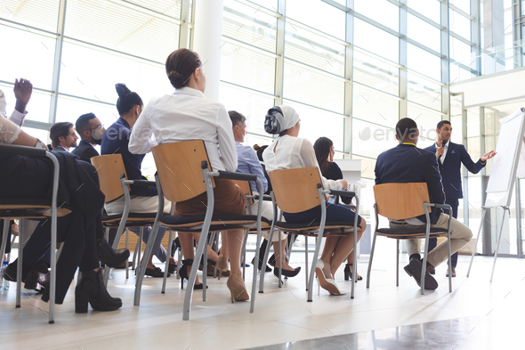 Businessman showing information on flip chart to group of diverse business people in conference room - Stock Photo - Images